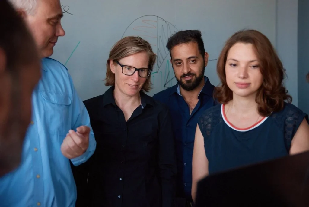 Team von Thetaris betrachtet gemeinsam einen Laptop vor einem Whiteboard